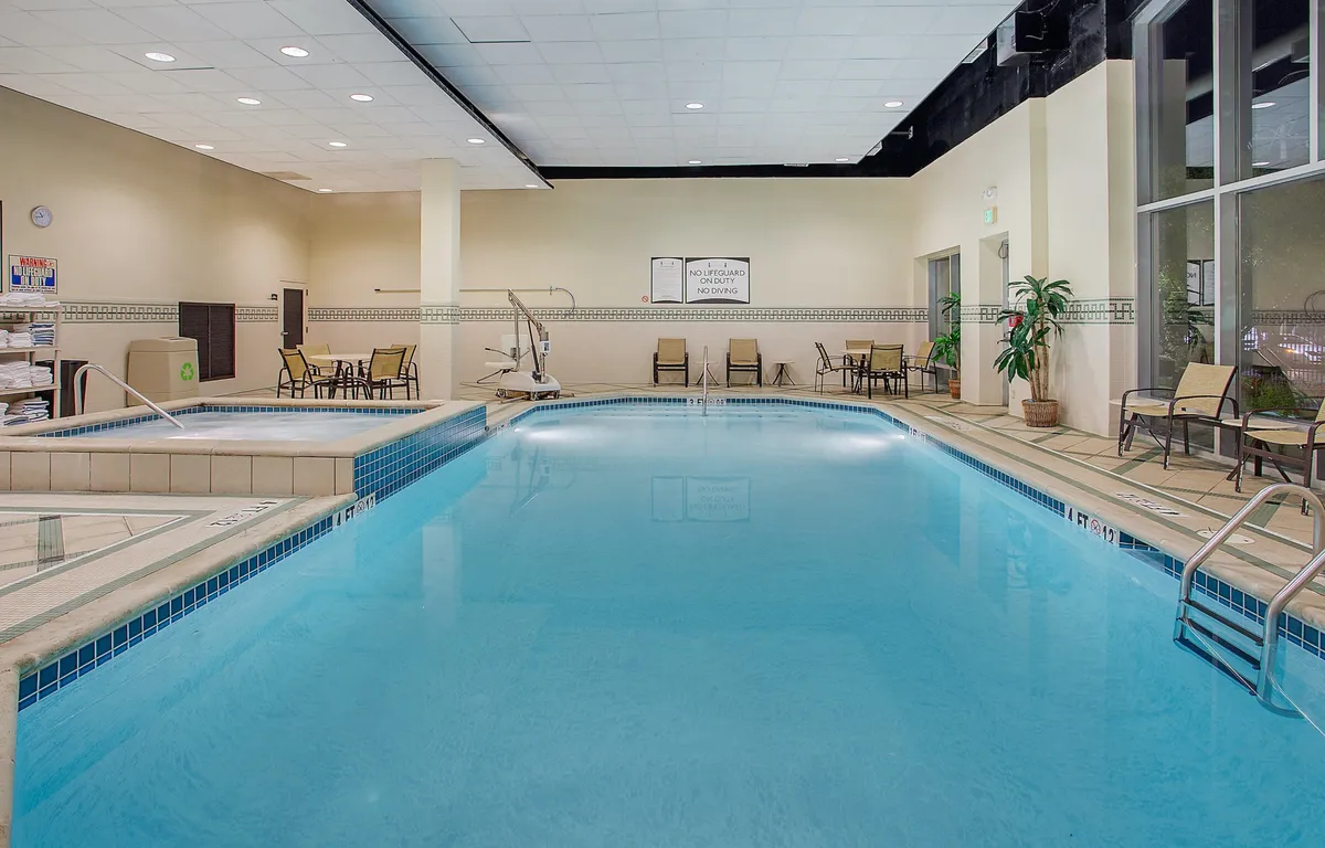 This image captures a tranquil indoor swimming pool area surrounded by lounge chairs and a water feature. The pool invites guests to unwind, socialize, or enjoy a refreshing swim after a busy day exploring local attractions.