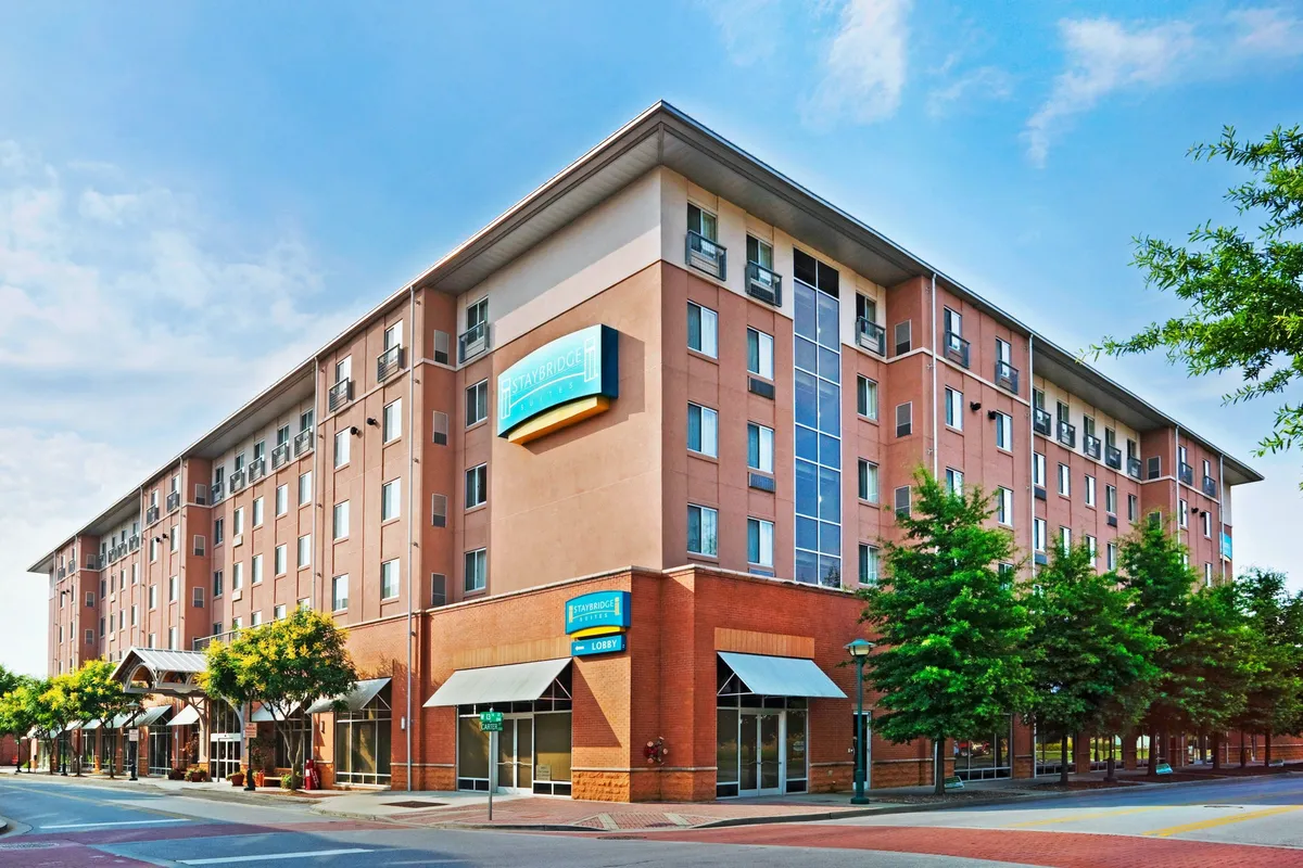 This image captures the exterior facade of the property, with prominent signage, a welcoming entrance, and well-maintained landscaping. Guests are seen checking in and enjoying the outdoor seating area, hinting at a lively, connected environment that encourages exploration of the surrounding neighborhood.